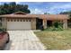 Charming single-story home featuring a stone facade, pergola-covered entryway, and a two-car garage at 1414 Serissa Ct, Orlando, FL 32818