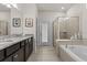 Bathroom featuring double sinks, granite countertops, tiled flooring, tub and glass enclosed shower at 1697 Kona Ln, Davenport, FL 33897