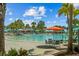 Beautiful pool area featuring palm trees, lounge chairs, picnic tables and covered bar with blue and orange umbrellas at 1697 Kona Ln, Davenport, FL 33897