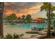 A beautiful pool with palm trees, lounge chairs, and umbrellas under a colorful sky at 1697 Kona Ln, Davenport, FL 33897