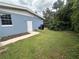 A view of backyard with side access, brick wall exterior, grass and greenery at 1951 S Crystal Lake Dr, Orlando, FL 32806