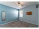 Minimalist bedroom with blue walls, ceiling fan, neutral carpet, a window, and blank bulletin board at 992 Jetway St, Orange City, FL 32763