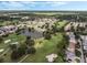 Aerial view of the community showcasing the golf course, lake, mature trees and manicured landscaping at 16950 Se 80Th Bellavista Cir, The Villages, FL 32162