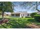 Spacious backyard showing the screened in sunroom, lush green lawn, and mature shade trees on a sunny day at 16950 Se 80Th Bellavista Cir, The Villages, FL 32162
