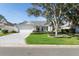 Charming single-story home featuring a well-manicured lawn, mature trees, and a two-car garage at 16950 Se 80Th Bellavista Cir, The Villages, FL 32162