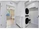 A laundry room with a stacked washer and dryer, a white cabinet, and a view into a bedroom at 693 Peyton Brooke Way, Winter Haven, FL 33881