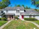 Charming townhome featuring a well-manicured lawn, gray facade, and a vibrant red front door at 1624 Rivers Edge Dr, Orlando, FL 32825