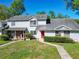 Traditional townhome features a well-manicured lawn, classic siding, a red front door, and mature trees at 1624 Rivers Edge Dr, Orlando, FL 32825