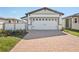 Exterior view of a house featuring a two-car garage with a brick driveway and manicured landscaping at 527 Kennedy Dr, Lake Alfred, FL 33850