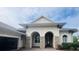 Home's stunning stucco exterior features an arched entryway with stone accents and a three-car garage at 5509 Meadow Hill Loop, Lady Lake, FL 32159