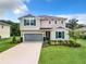 Charming two-story home featuring a gray garage door, blue shutters, and a well-maintained lawn and landscaping at 8060 Cherrystone St, Leesburg, FL 34748