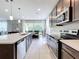 Modern kitchen featuring stainless steel appliances, dark cabinets, a quartz island, and an open layout at 8060 Cherrystone St, Leesburg, FL 34748