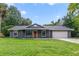 A ranch home's exterior showcases a well-manicured lawn, a gray facade, an orange front door and a two car garage at 668 Coral Way, Winter Springs, FL 32708