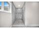 Modern shower with marble-look tiled walls, mosaic tile floor and natural light from a window at 15062 Sw 63Rd Court Rd, Ocala, FL 34473