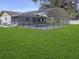 Backyard featuring a screened-in pool enclosure, lush green grass, and privacy fencing at 4814 Lake Shore Dr, St Cloud, FL 34772