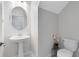 Modern powder room with pedestal sink, toilet, and circular mirror at 2275 Cathedral Rock Dr, Kissimmee, FL 34746