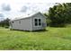 A cozy, light-gray cottage featuring a white-trimmed window and a modern air conditioning unit at 575 2Nd St, Oviedo, FL 32765
