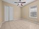 Simple bedroom with tile floor, window, ceiling fan, and closet space at 143 Brunswick Dr, Davenport, FL 33837