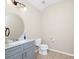 This powder room has a round mirror over a gray vanity, tile floors and light fixtures at 15558 Sandfield Loop, Winter Garden, FL 34787