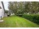 Well-manicured backyard with lush green lawn, mature trees, and privacy hedge at 16695 Broadwater Ave, Winter Garden, FL 34787