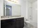 Bathroom featuring double granite vanity, dark cabinets, tiled floors, and a well lit mirror at 16695 Broadwater Ave, Winter Garden, FL 34787