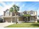 A two-story home with tan exterior, three car garage, manicured lawn and two palm trees at the front at 14126 Fox Glove St, Winter Garden, FL 34787