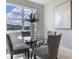Cozy dining area with round glass table, upholstered chairs, natural light from the window, and modern art at 16033 Barkly Ridge Ct, Winter Garden, FL 34787