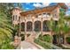 Elegant multi-story home with arched windows, a grand staircase, and lush tropical landscaping at 6324 Deacon Cir, Windermere, FL 34786