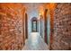 A hallway with brick walls, stone flooring, sconces, and a stained glass window at the end at 6324 Deacon Cir, Windermere, FL 34786
