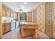 Traditional kitchen with natural wood cabinets, an island, and a window providing natural light and an adjacent laundry area at 6324 Deacon Cir, Windermere, FL 34786