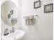 A well-lit powder room with a pedestal sink, oval mirror, decorative towels, and framed art at 15259 Willow Arbor Cir, Orlando, FL 32824