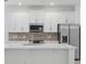 Modern kitchen featuring white cabinets, stainless steel appliances, and a stylish backsplash at 2585 Cavanaugh Dr, Orlando, FL 32817