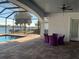 Covered patio area with purple seating, looking out to the pool, screened enclosure, and waterfront view at 816 Johns Point Dr, Oakland, FL 34787