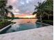 Stunning infinity pool overlooking a serene lake at sunset, surrounded by lush greenery and palm trees at 1010 Strathmore Dr, Orlando, FL 32806