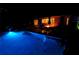 Inviting pool area at night, illuminated by bright blue lights with a backyard entertainment area and fire pit at 1010 Strathmore Dr, Orlando, FL 32806