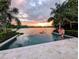Sunset view from the pool overlooking the lake, enhanced by travertine pavers and lush, mature palm trees at 1010 Strathmore Dr, Orlando, FL 32806