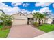 Inviting home featuring a two-car garage and a red brick driveway, complemented by lush landscaping and curb appeal at 886 Grazie Loop, Davenport, FL 33837