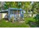 Charming blue shed with a porch and landscaping at 1713 Longleaf Dr, Saint Cloud, FL 34769