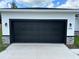 A black garage door on a stucco home with stone accents, and address number visible at 442 Marion Oaks Crse, Ocala, FL 34473