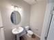 Stylish half-bathroom with a pedestal sink, oval mirror, and contemporary lighting fixtures, offering functionality and charm at 791 Pilea St, Apopka, FL 32703
