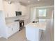 Modern kitchen features white cabinets, stainless steel appliances, and an island with a sink, open to the living area at 791 Pilea St, Apopka, FL 32703