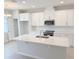 Bright kitchen boasts white cabinetry, stainless steel appliances, quartz countertops and island with sink at 791 Pilea St, Apopka, FL 32703