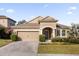 Tan single-story house with a two-car garage and manicured lawn at 8162 Lazy Bear Ln, Winter Park, FL 32792