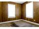 Cozy bedroom featuring wood-paneled walls and bright natural light from two windows at 1017 Mabbette St, Kissimmee, FL 34741