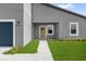 Close-up of the home's entrance featuring a modern wood door, neutral trim, and green landscaping at 4683 Sw 136Th St, Ocala, FL 34473