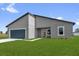 Modern gray home featuring a blue garage door, minimalist landscaping, and a well-maintained green lawn at 4683 Sw 136Th St, Ocala, FL 34473