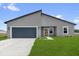 Modern gray home with a blue garage door, green lawn, and minimalist landscaping under a sunny blue sky at 4683 Sw 136Th St, Ocala, FL 34473