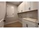 Well-lit laundry room featuring white cabinetry, tile floor, a sink, and modern fixtures at 3255 Roseville Dr, Apopka, FL 32712