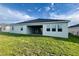 Exterior view of home's backyard with a covered patio, well-maintained lawn and a clear blue sky at 3271 Roseville Dr, Apopka, FL 32712