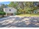 Exterior view of a white home with a spacious garage, lush landscaping, and extended driveway at 1822 Se 8Th St, Ocala, FL 34471